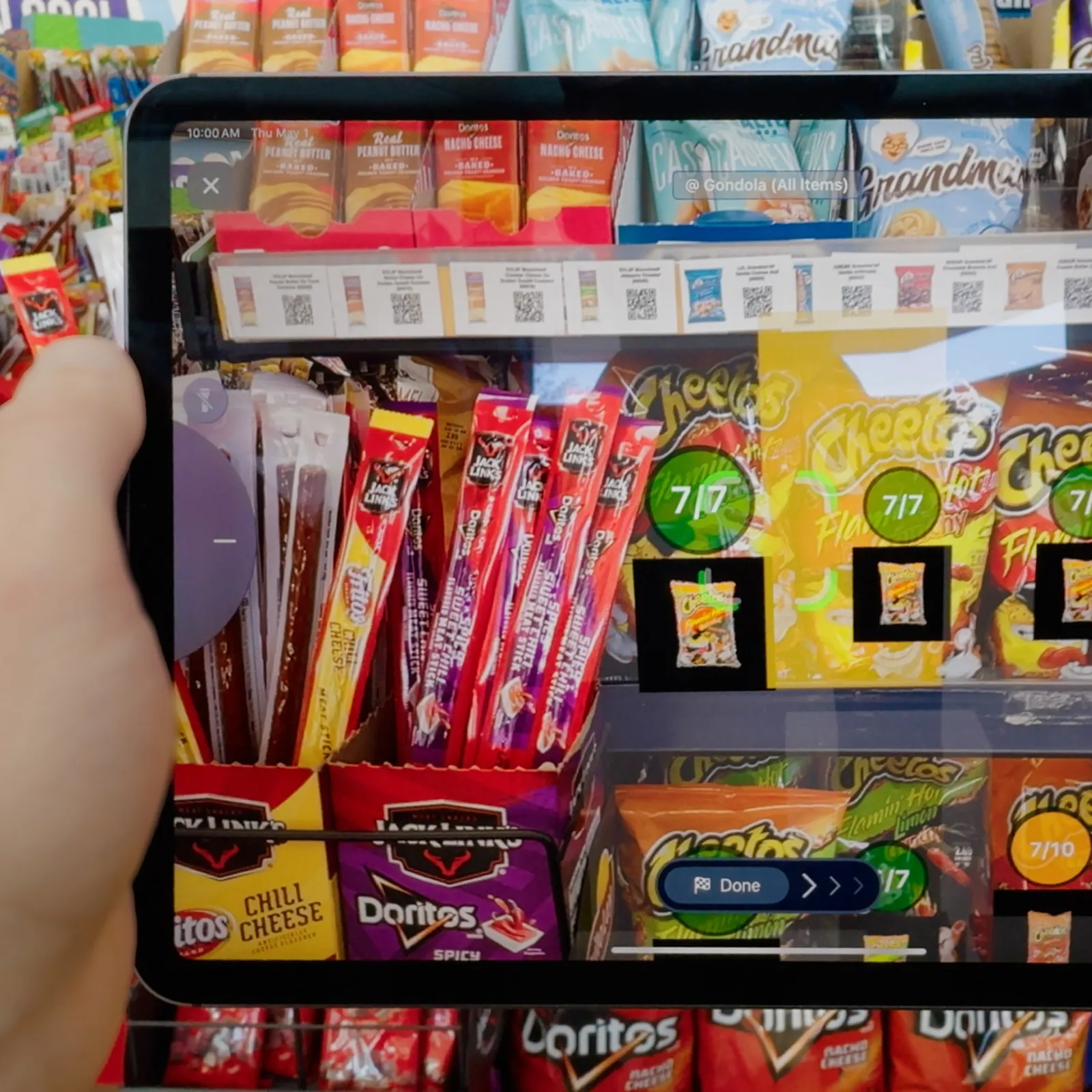 Close up of an employee scanning various snacks on a shelf with NomadGo on a tablet.