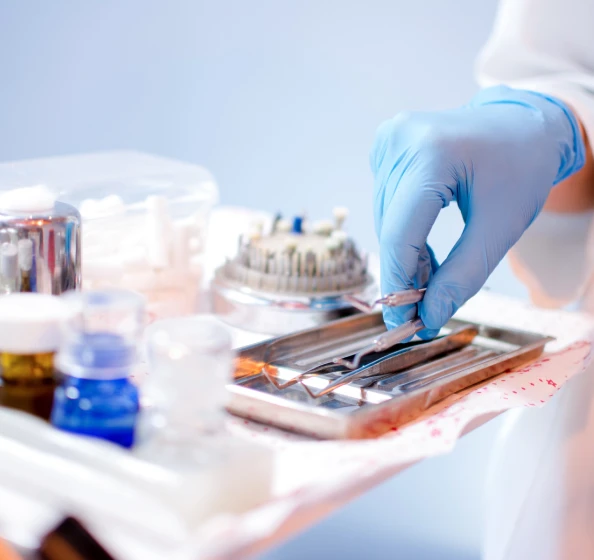 Gloved hand picking up operating tools from a tray in an operating room