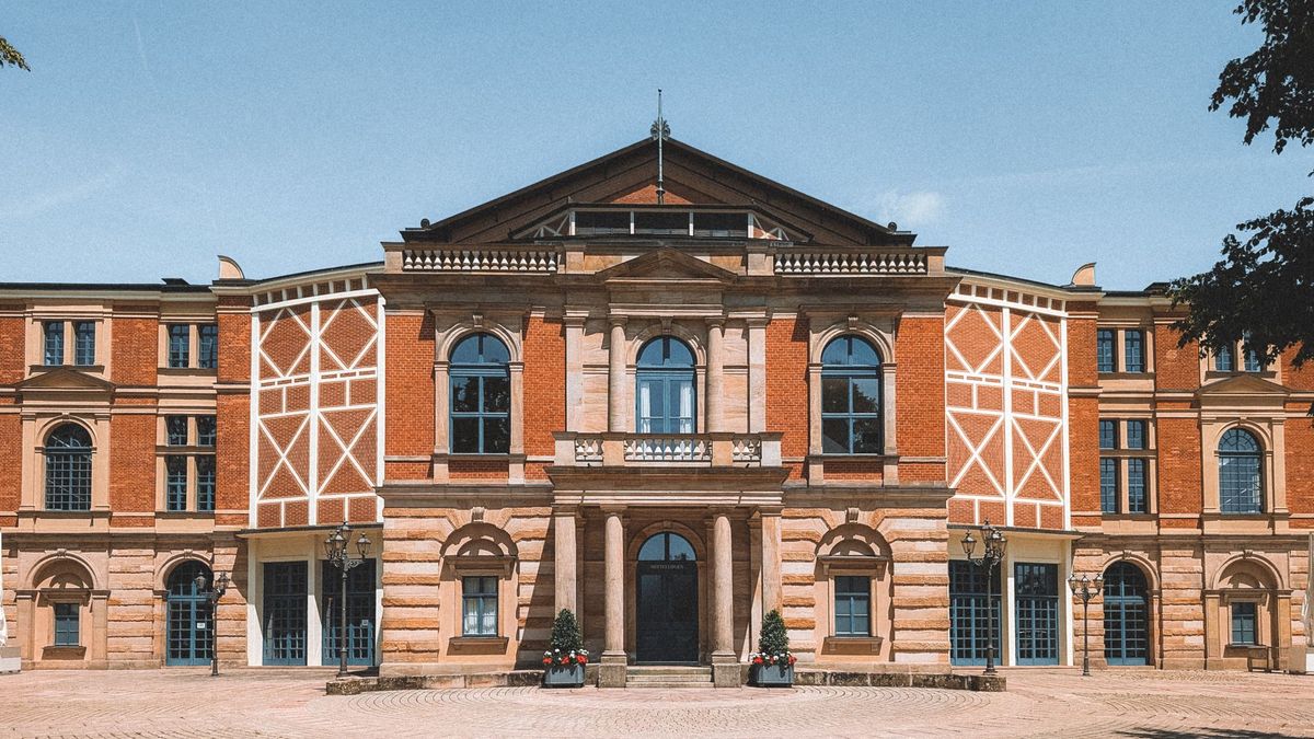 Fassade des Bayreuther Festspielhauses mit Fachwerk und Backstein unter blauem Himmel