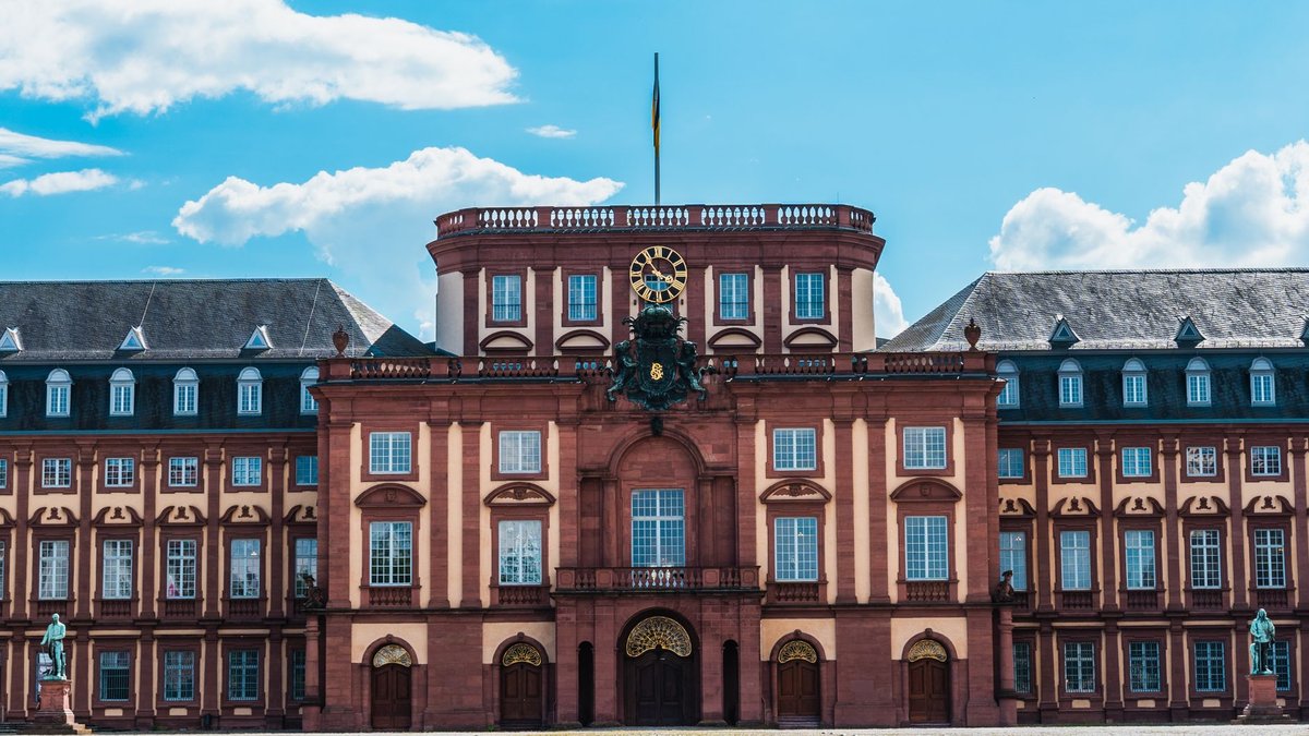 Die Mittelfassade des Mannheimer Schlosses mit Uhr und Wappen an einem sonnigen Tag