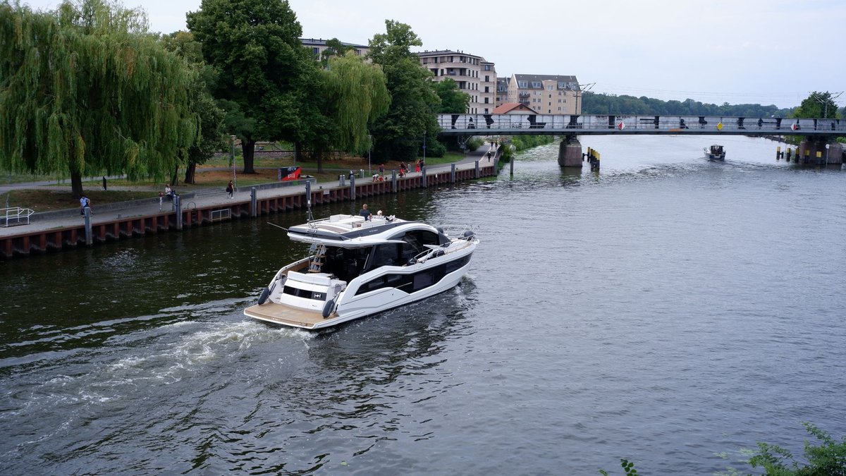 Motorboot auf der Havel in Potsdam, am Ufer Bäume und eine Uferpromenade