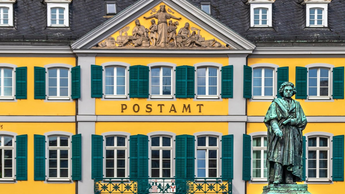Das Beethoven-Denkmal vor der gelben Fassade des alten Postamts am Münsterplatz in Bonn