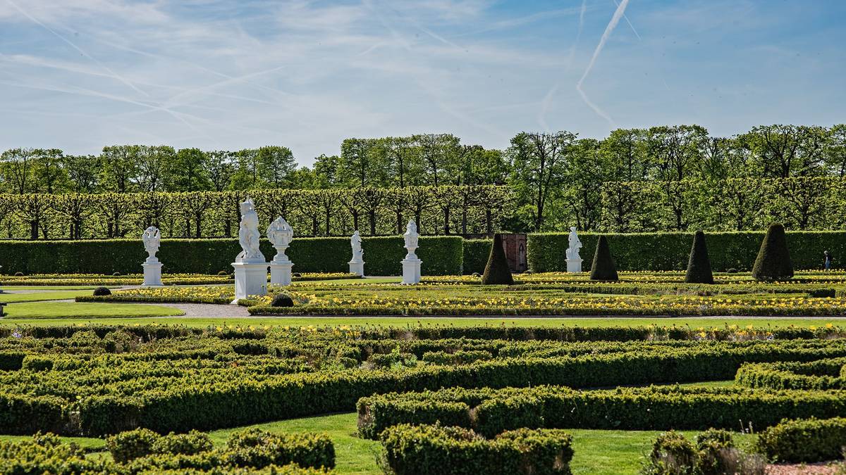 Beschnittene Hecken und weiße Statuen im Großen Garten der Herrenhäuser Gärten unter blauem Himmel