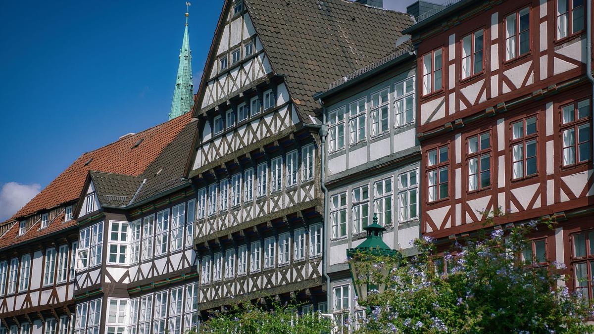 Reihe restaurierter Fachwerkhäuser in der Altstadt von Hannover mit Kirchturm im Hintergrund