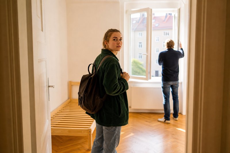 Studentin besichtigt ein leeres Zimmer in einer Altbauwohnung