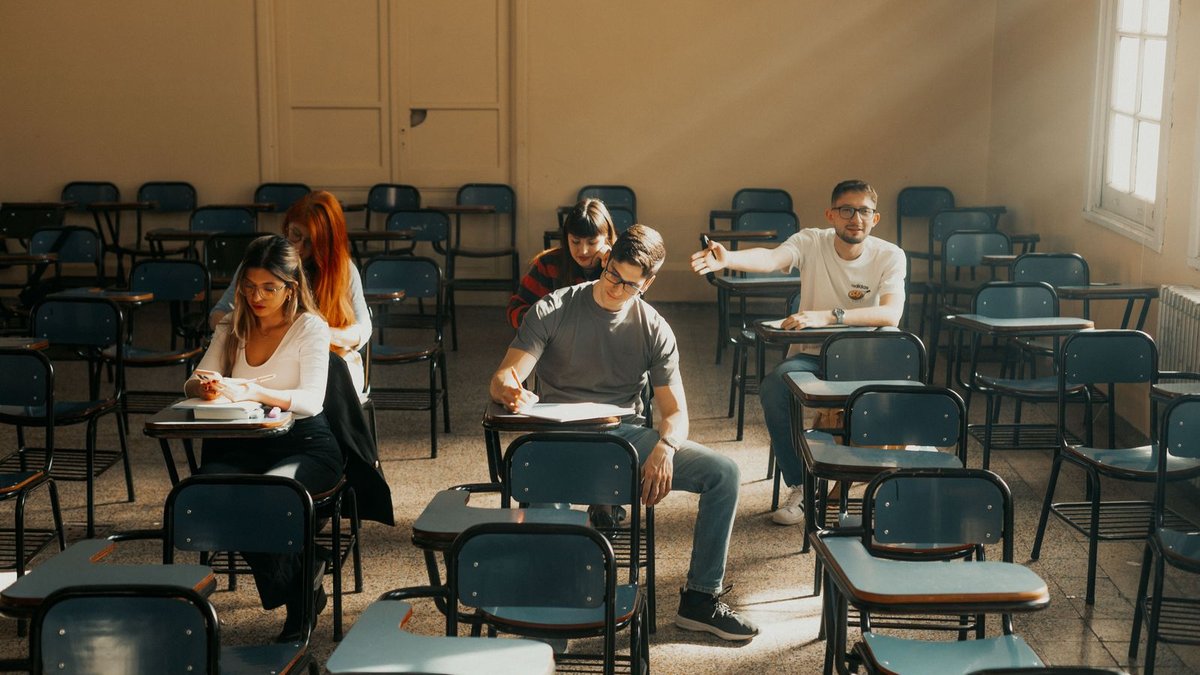 Studierende sitzen mit Abstand in einem Hörsaal und schreiben eine Klausur