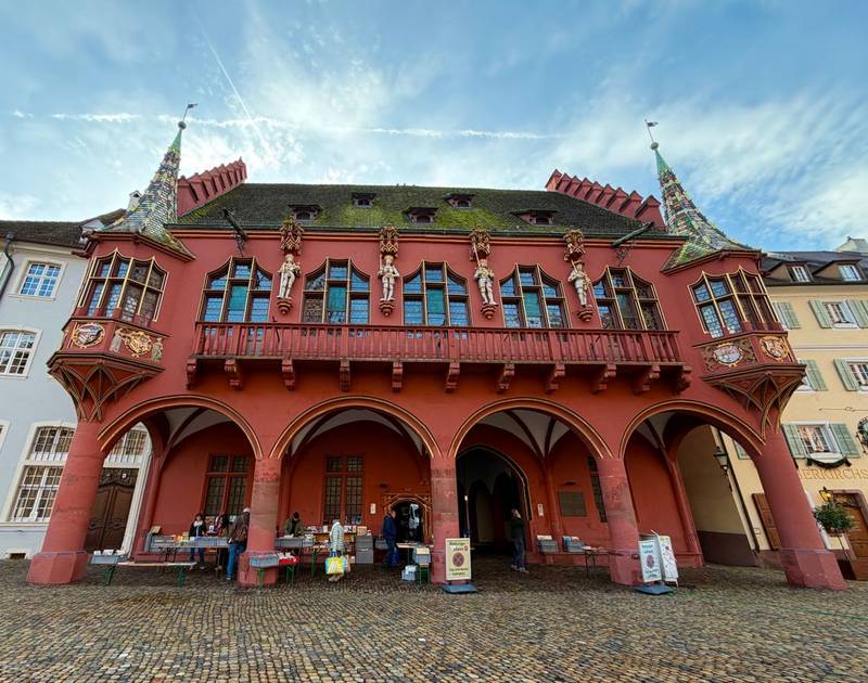 Das rote Historische Kaufhaus am Freiburger Münsterplatz mit seinen Arkaden