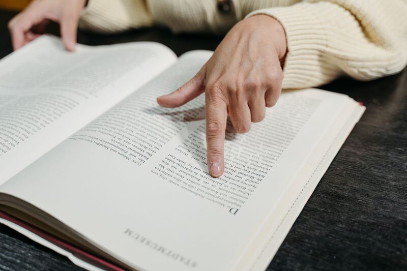 Ein Finger zeigt auf eine Textstelle in einem aufgeschlagenen Buch