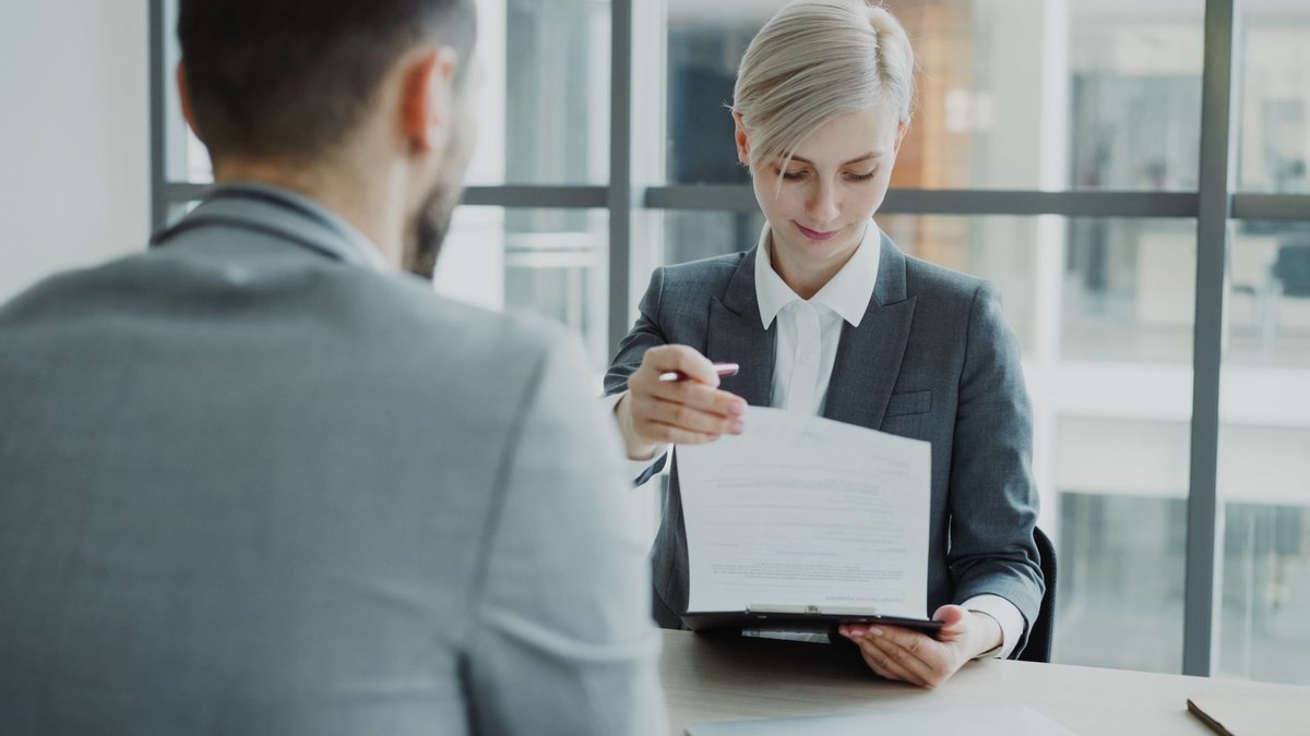Zwei Personen im Büro besprechen ein Vertragsdokument über den Tisch hinweg