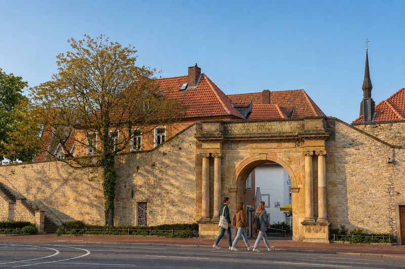 Studierende gehen bei Abendsonne durch das Heger Tor in der Osnabrücker Altstadt