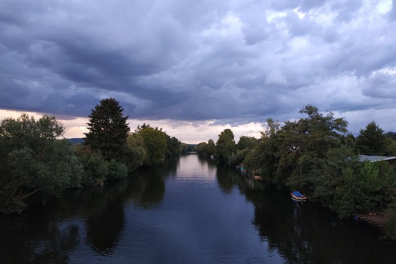 Die Lahn bei Gießen am Abend, von einer Brücke aus flussaufwärts fotografiert, mit Bäumen an beiden Ufern