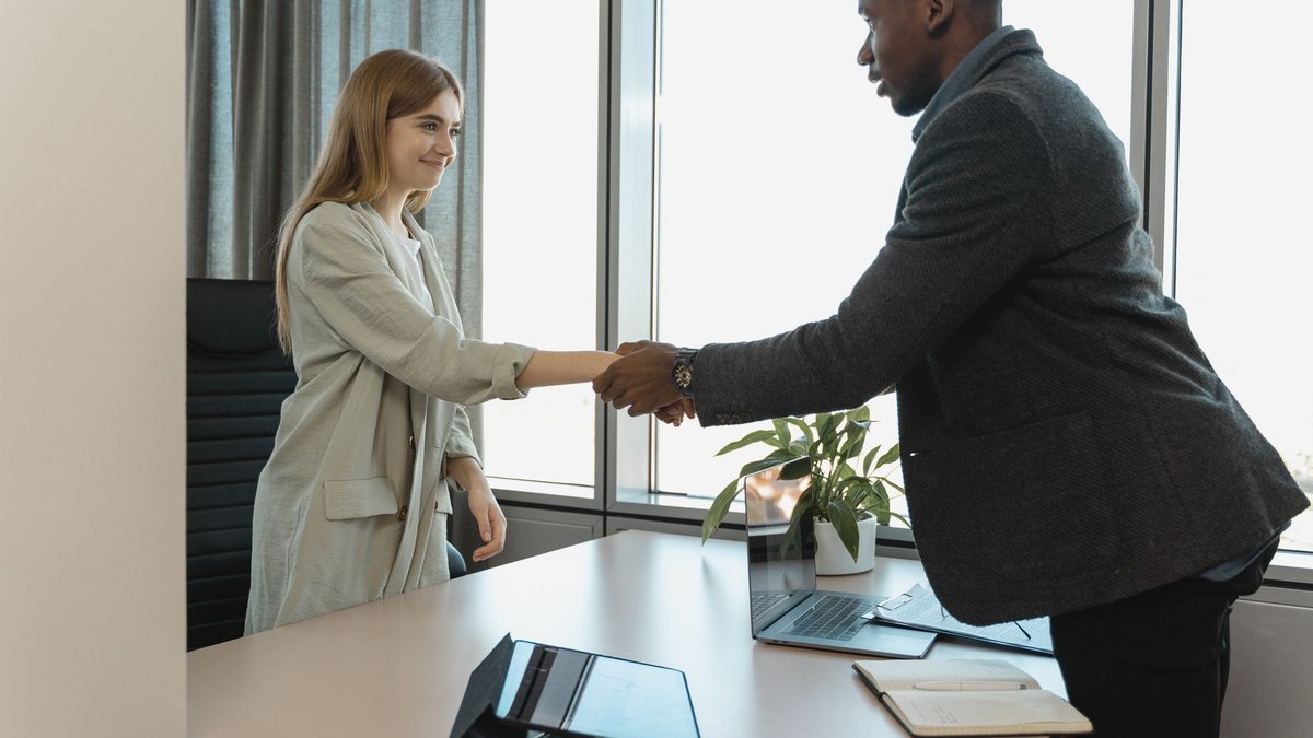 Bewerberin und Kanzleipartner geben sich am Ende eines Bewerbungsgesprächs die Hand
