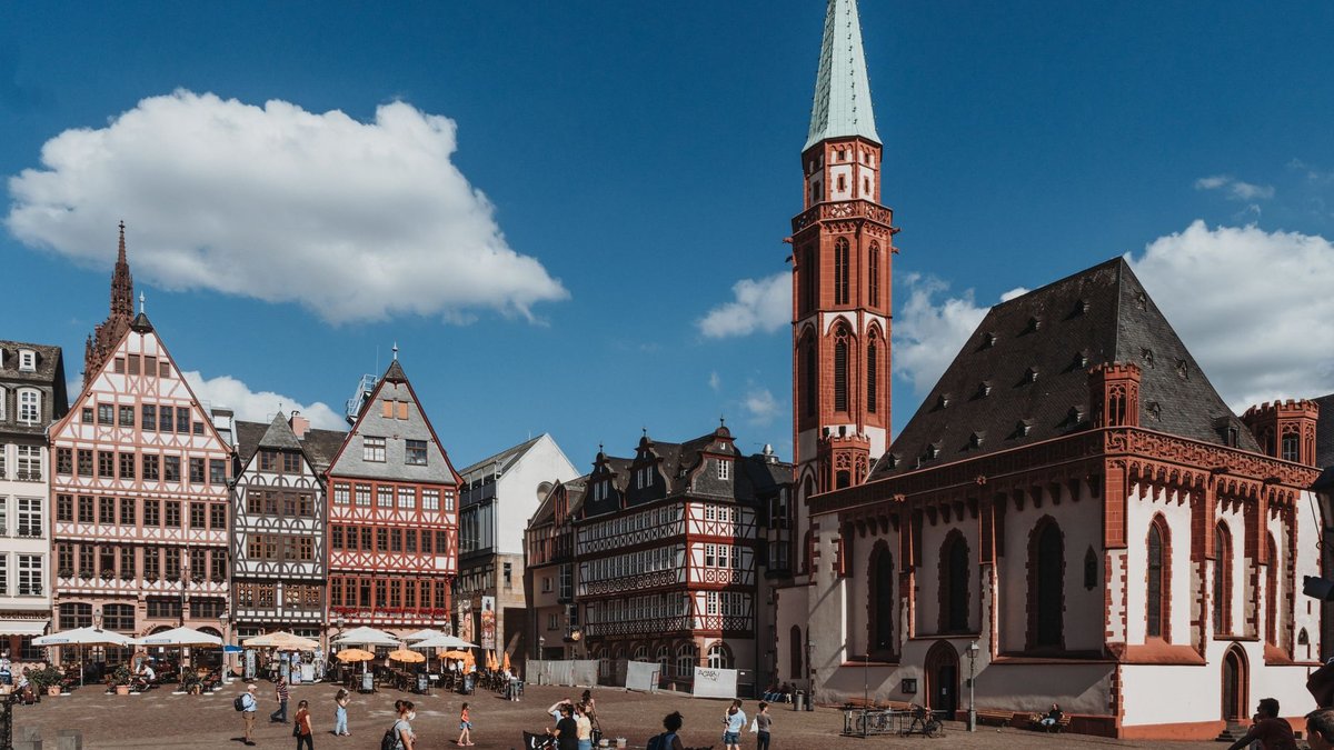 Römerberg in Frankfurt mit Fachwerkhäusern, der Alten Nikolaikirche und Passanten auf dem Platz