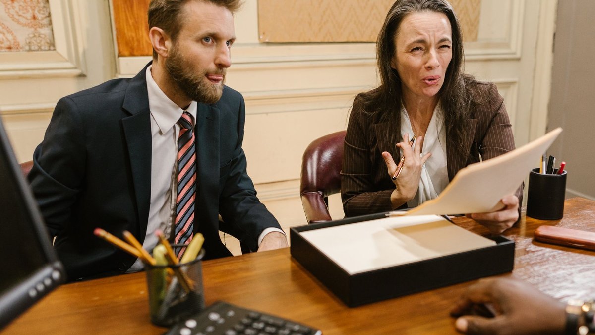 Zwei Anwälte im holzvertäfelten Büro besprechen Unterlagen mit einer Mandantin