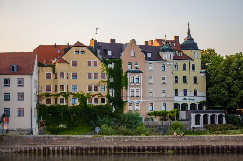 Bunte Altbauten am Donauufer in Regensburg im Abendlicht