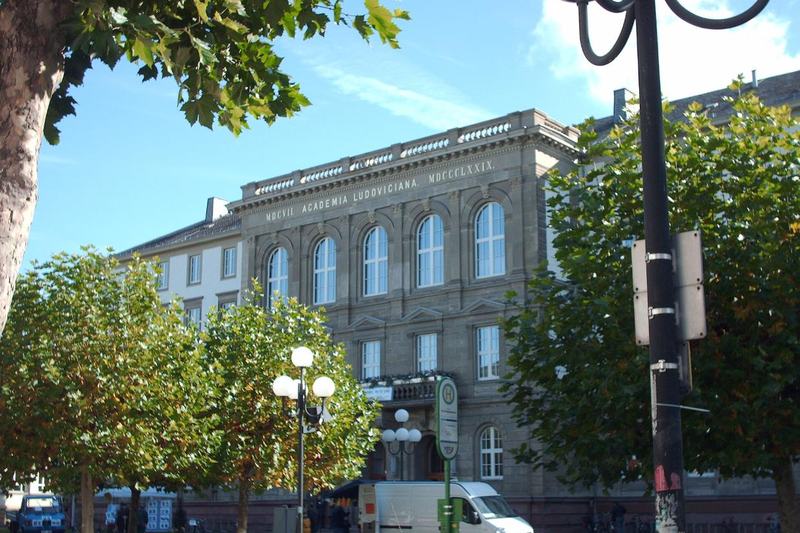 Das Hauptgebäude der Justus-Liebig-Universität Gießen mit der Inschrift Academia Ludoviciana, davor Platanen an der Ludwigstraße