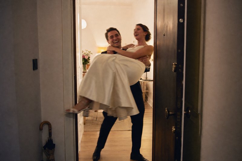 Ein Bräutigam trägt seine lachende Braut über die Schwelle der gemeinsamen Wohnung