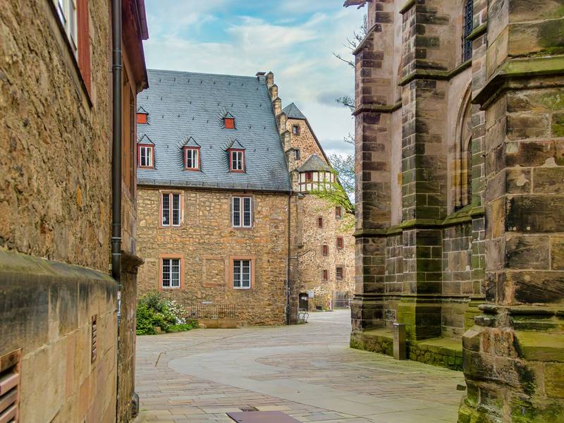 Gasse in der Marburger Altstadt mit historischem Bruchsteinhaus und gotischem Kirchenbau