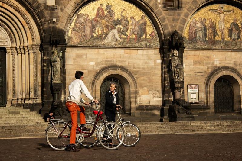 Zwei junge Leute stehen mit Fahrrädern vor dem Portal des Bremer Doms