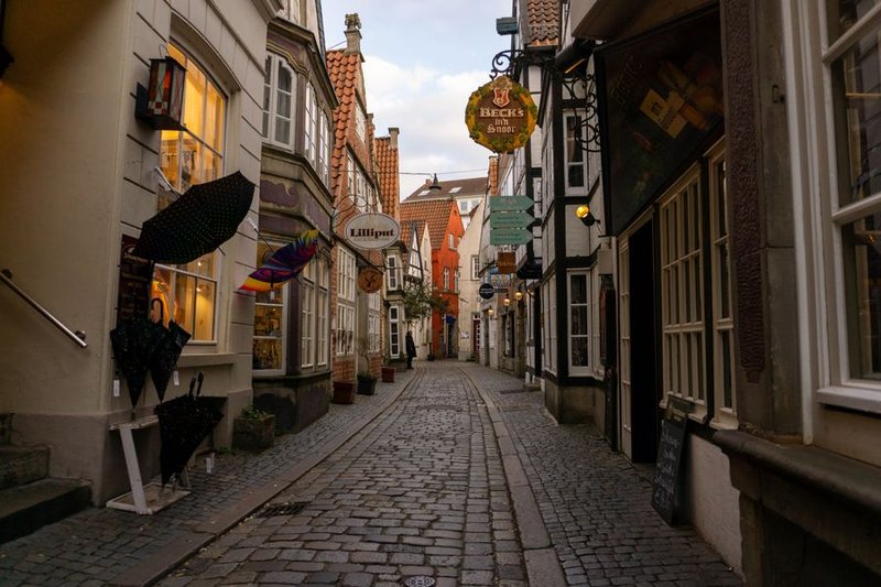 Kopfsteinpflastergasse im Bremer Schnoorviertel mit beleuchteten Läden und Kneipenschildern