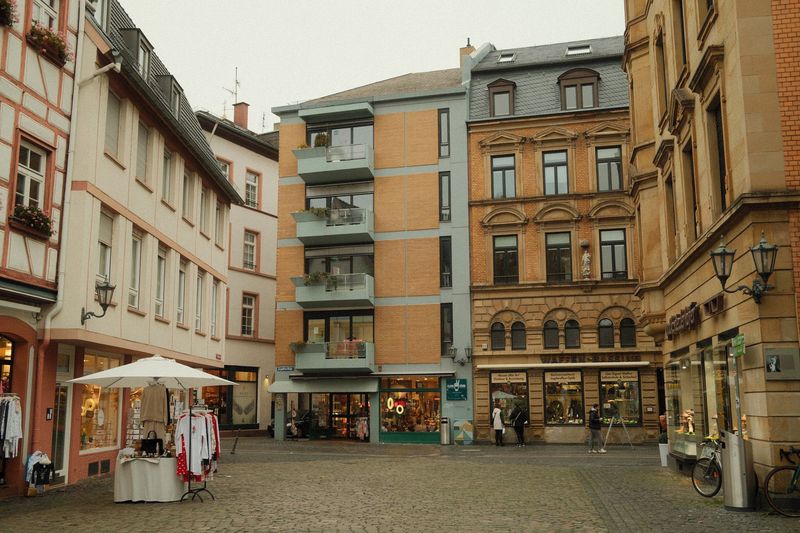 Gasse in der Mainzer Altstadt mit Fachwerkhaus, Laden und einem Marktstand unter einem Sonnenschirm