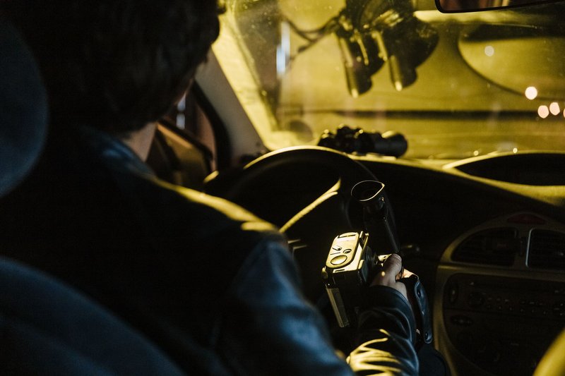 Person von hinten, die nachts aus einem Auto heraus mit einer Kamera filmt