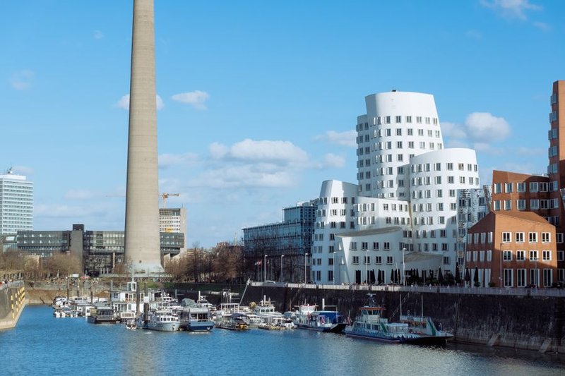 Der Düsseldorfer Medienhafen mit den geschwungenen Gehry-Bauten am Neuen Zollhof und Booten im Hafenbecken