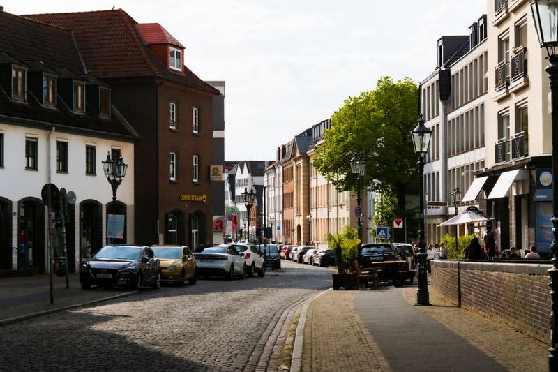 Sonnige Kopfsteinpflasterstraße in der Düsseldorfer Innenstadt mit alten Gaslaternen und historischen Fassaden