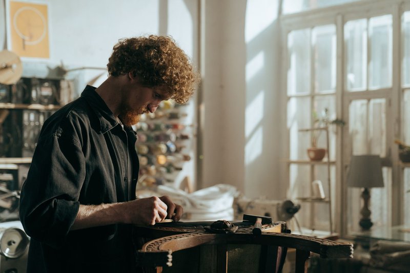 Handwerker arbeitet in einer hellen Werkstatt an einem alten Möbelstück