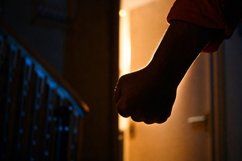 Geballte Faust im Gegenlicht einer offenen Tür, Unterarm angeschnitten, kein Gesicht erkennbar