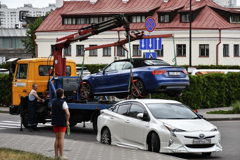 Abschleppwagen hebt einen blauen Pkw neben einem Halteverbotsschild von der Straße.