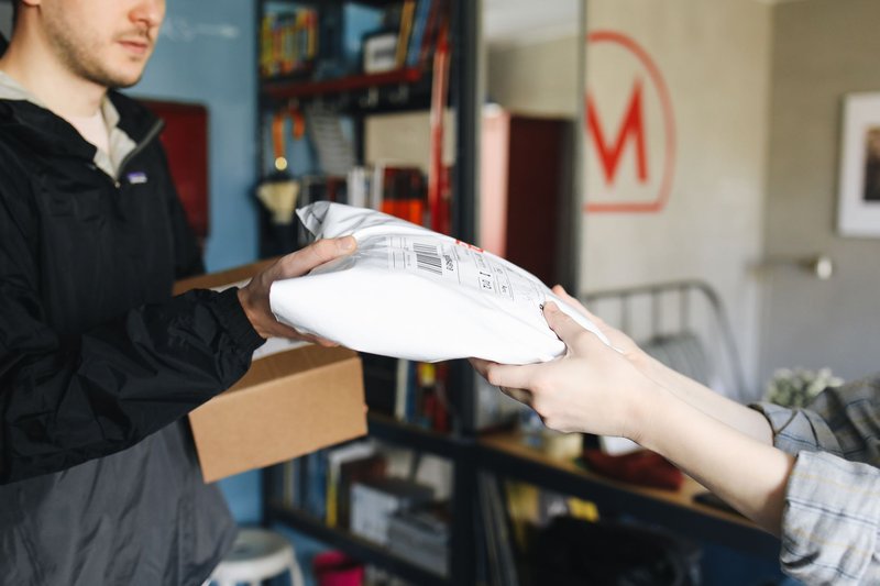 Ein Paket wird von einer Person an eine andere in einem Innenraum übergeben