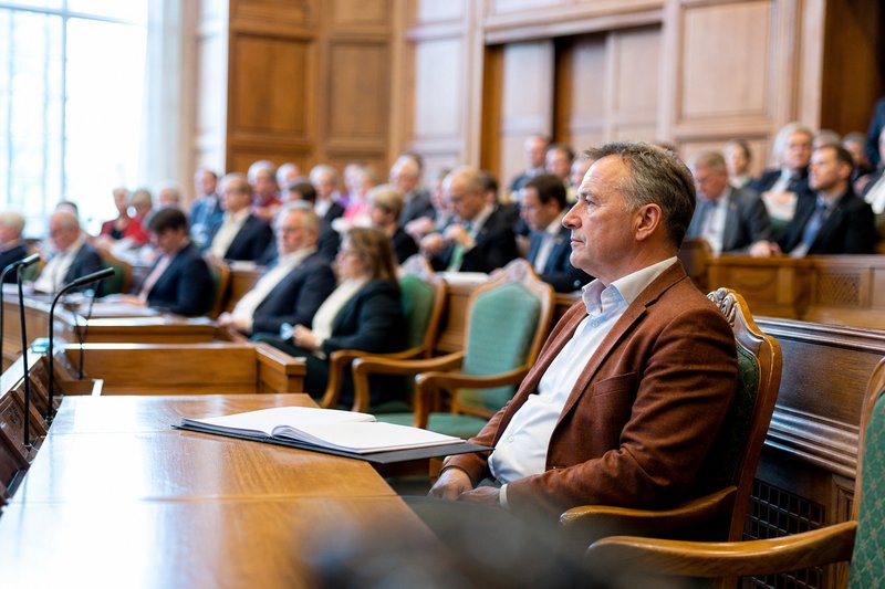 Ein Abgeordneter sitzt allein am äußeren Ende einer Sitzreihe, dahinter eine dicht besetzte Sitzgruppe