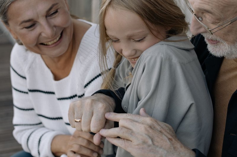 Großmutter und Großvater halten lachend die Hände ihres Enkelkindes