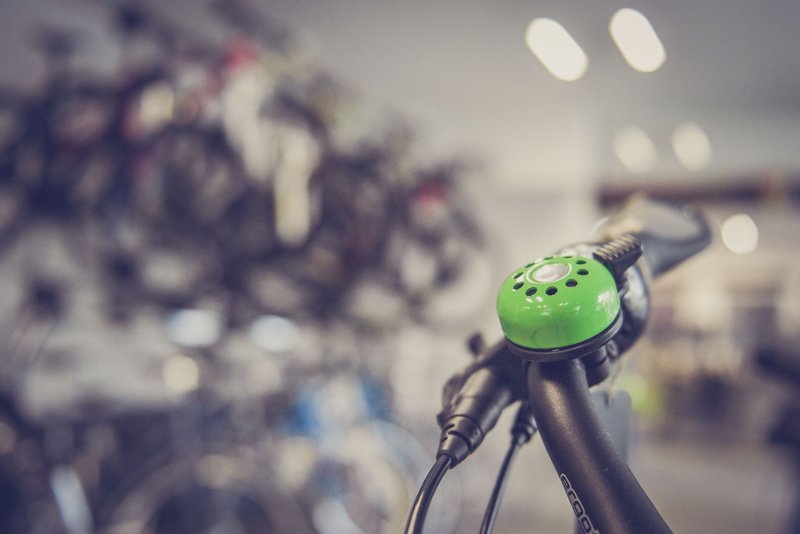 Fahrradklingel und Lenker im Vordergrund, dahinter die Reihen eines Fahrradladens