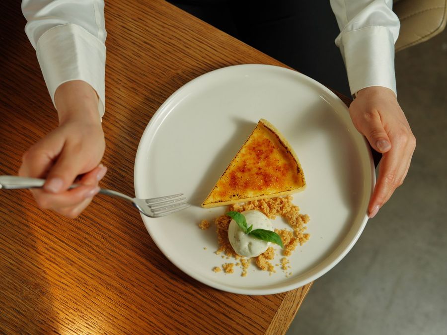 Servierkraft stellt einen Teller mit einem Dessert auf einen Holztisch
