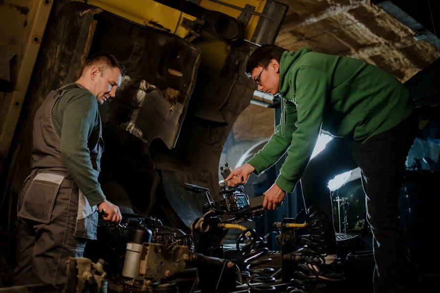 Zwei Mechaniker arbeiten in einer Werkstatt gemeinsam an einem ausgebauten Motor