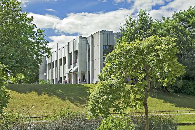 Zentralbibliothek der Universität Augsburg hinter Bäumen und Grünflächen