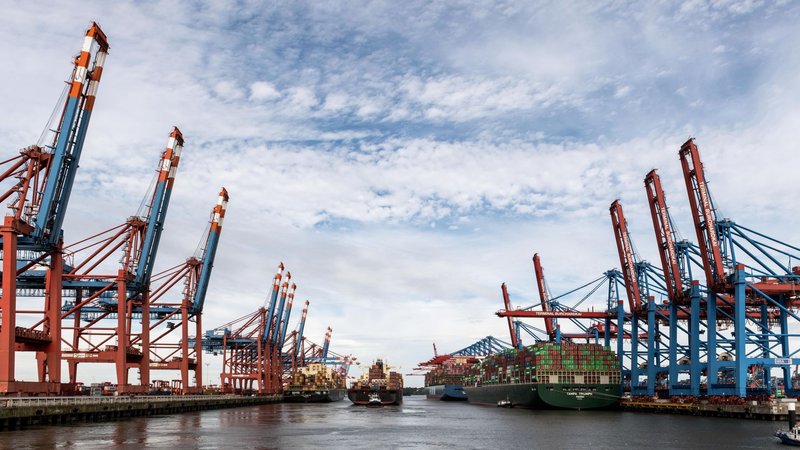 Containerterminal im Hamburger Hafen mit Verladekränen an beiden Kaiseiten und Containerschiffen im Fahrwasser