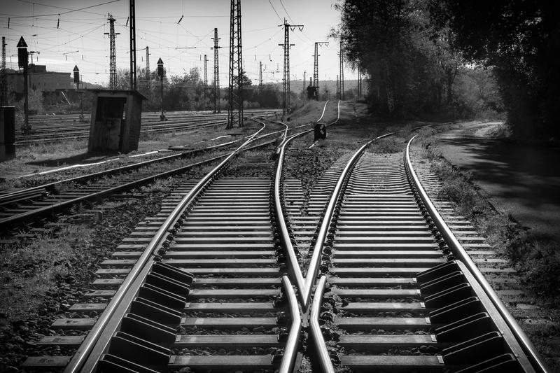 Bahngleise mit einer Weiche, Blick in Schwarzweiß entlang der Schienen