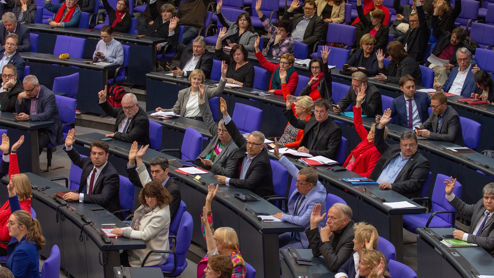 Abgeordnete im Plenarsaal des Deutschen Bundestages heben bei einer Abstimmung die Hand