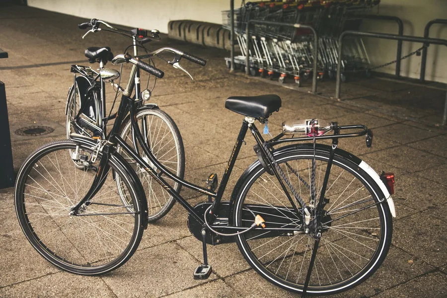 Zwei baugleiche schwarze Fahrräder nebeneinander abgestellt