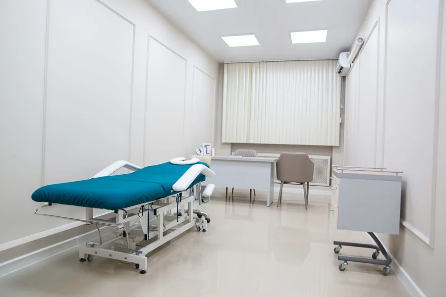 Leerer Behandlungsraum einer Therapiepraxis mit Behandlungsliege und Schreibtisch