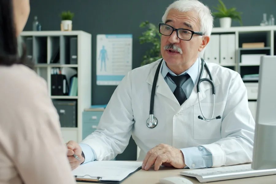 Arzt bespricht mit einer Patientin am Schreibtisch die Ergebnisse einer Untersuchung