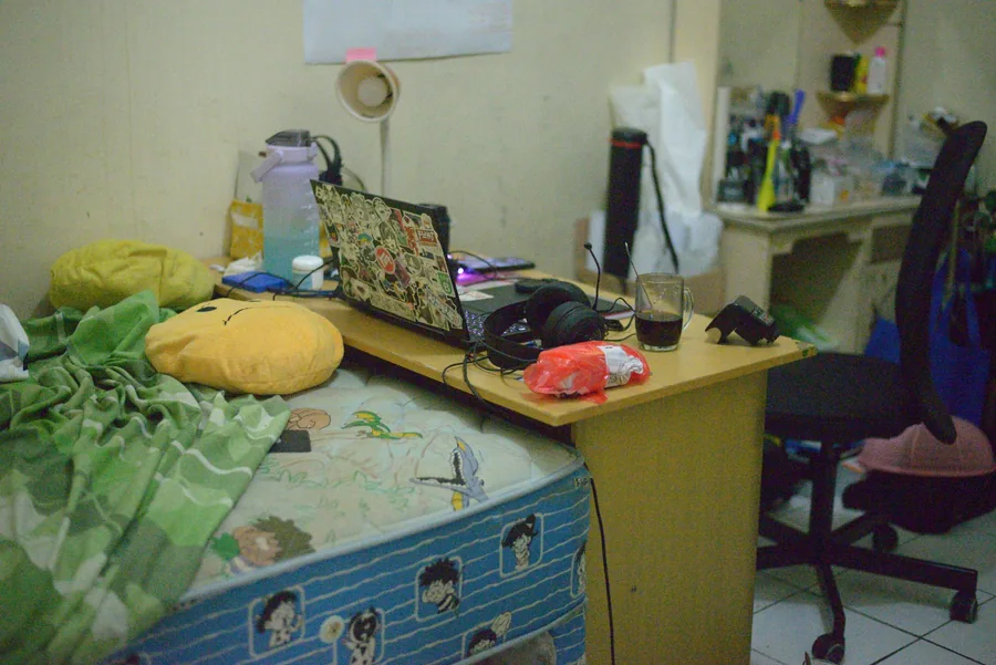 Bewohntes Zimmer in einem Studentenwohnheim mit Schreibtisch, Bett und Büchern
