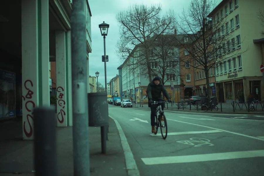 Radfahrer fährt an einer Reihe geparkter Autos in einer Innenstadtstraße vorbei