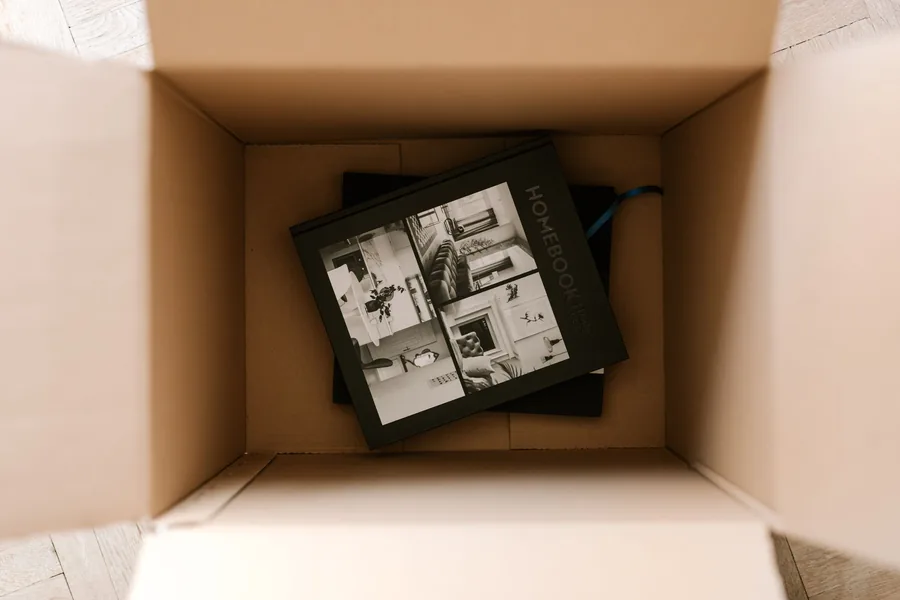 Geöffnetes Paket mit einem Buch darin auf dem Wohnzimmerboden.