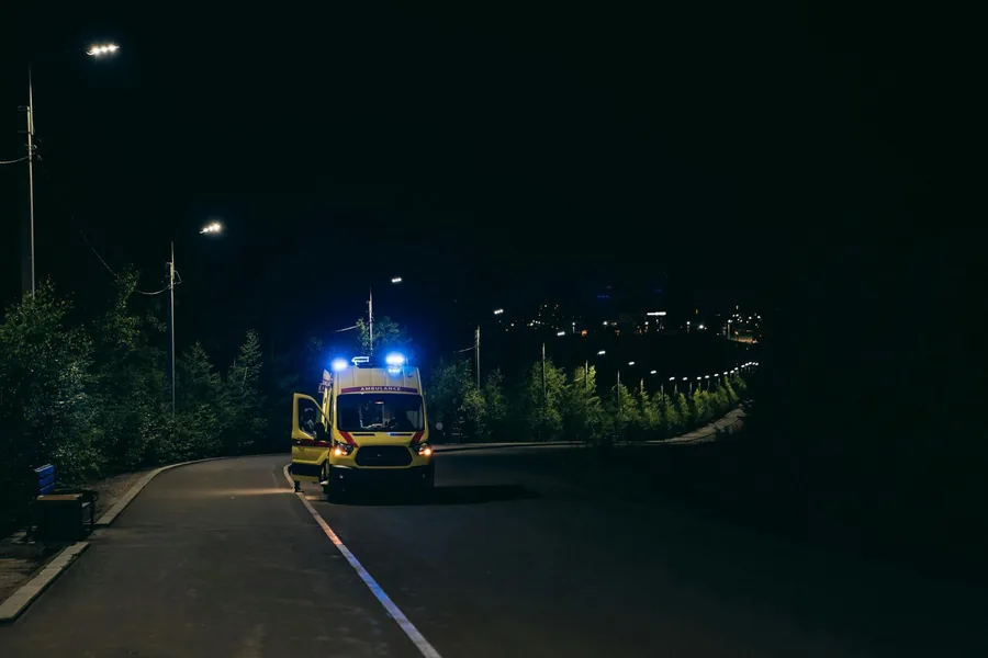 Rettungswagen mit eingeschaltetem Blaulicht nachts auf einer Straße
