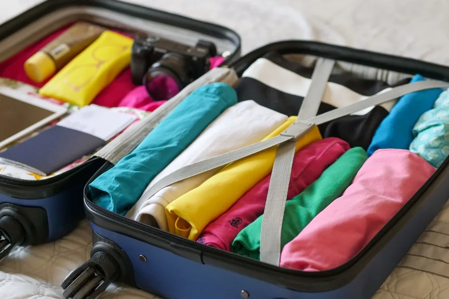 Gepackter Reisekoffer mit gefalteter Kleidung und Reisepass, von oben fotografiert