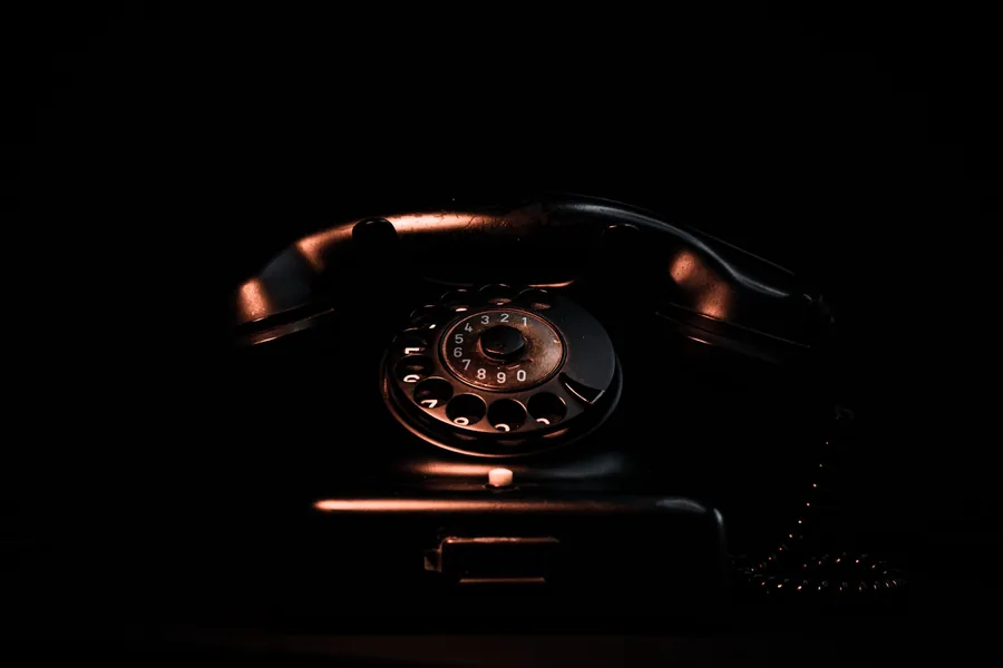 Altes Wählscheibentelefon mit Hörer in dunkler, warm beleuchteter Umgebung
